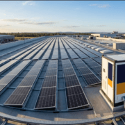 SunLith Energy Rooftop solar panels stretch in long rows on a flat commercial roof under a clear sky. A large utility unit sits at the right side of the roof.