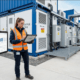 BESS Specifications Datasheet Review — SunLith Energy - SunLith Energy SunLith Energy Engineer reviewing BESS technical specification sheet on tablet in front of battery storage container